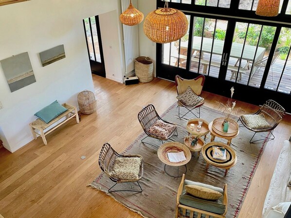 Una habitació àmplia amb un gran finestral, mobles de vimetes i una catifa teixida.