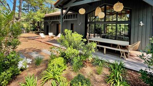 Una cabaña de madera con terraza, mobiliario exterior y jardín.
