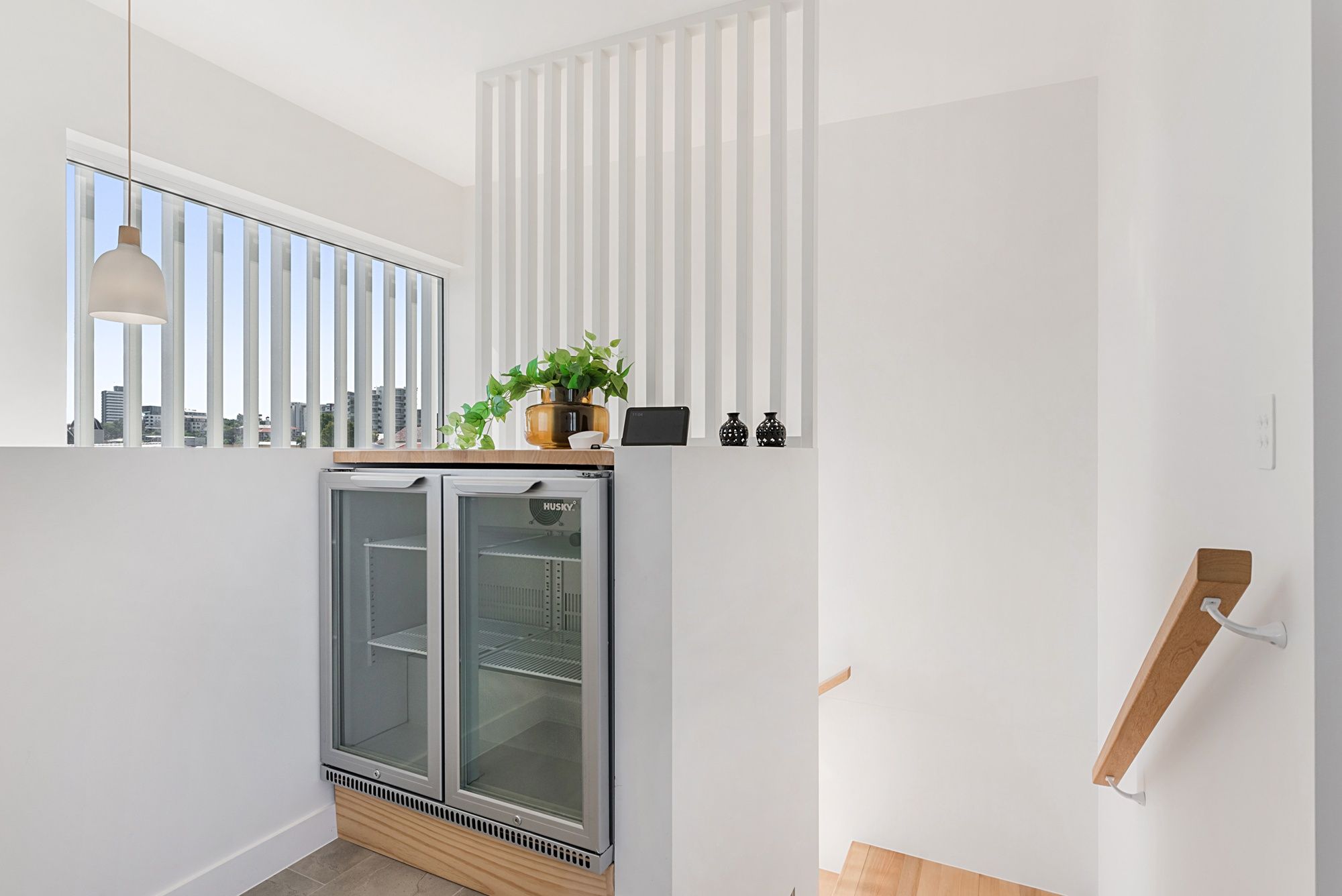 A modern kitchen with a built-in refrigerator, a window with blinds, and a wooden countertop.