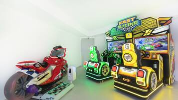 Quarto com jogos de corrida de fliperama, incluindo um jogo de moto e um jogo de corrida de ônibus.