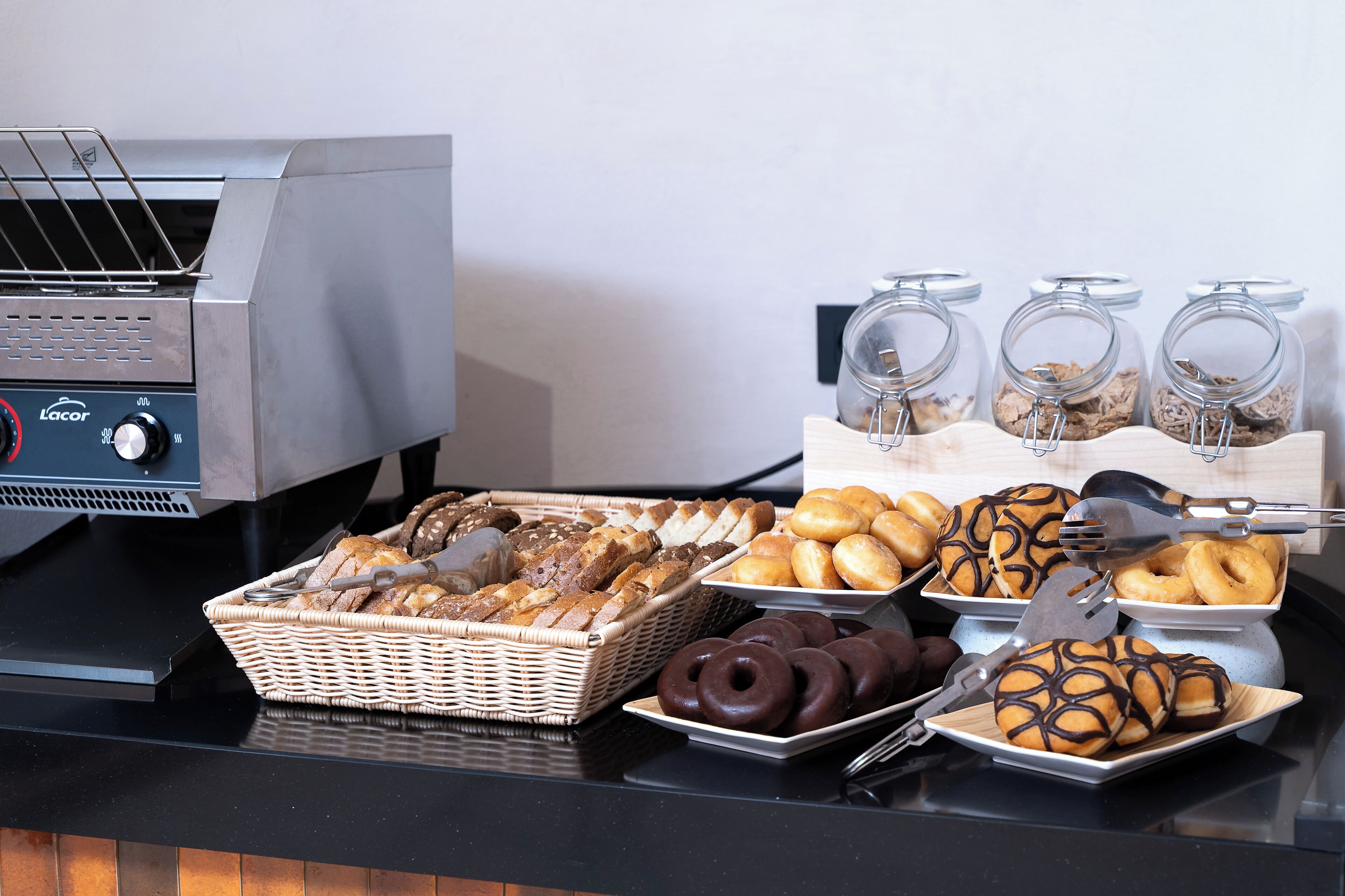 A breakfast buffet with various breads, pastries, and donuts.