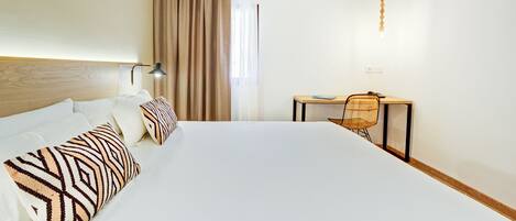 Ein Hotelzimmer mit einem großen Bett, einem Schreibtisch, einem Stuhl und einer Lampe.