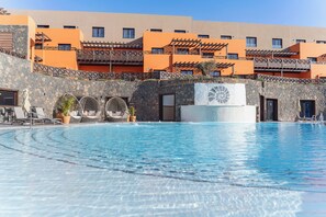 Una piscina con lettini e un muro in pietra.