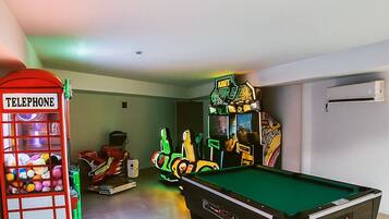 A pool table, a telephone booth, and arcade games in a room.