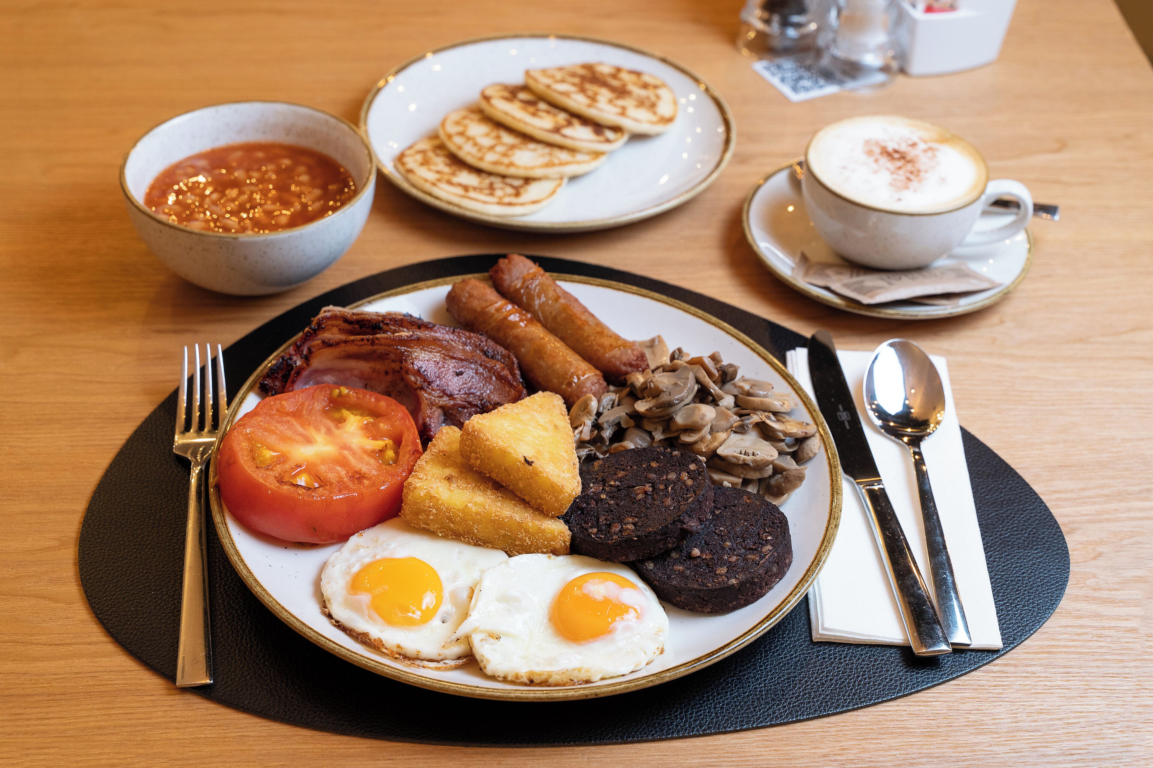 A breakfast plate with eggs, bacon, sausages, mushrooms, and toast.