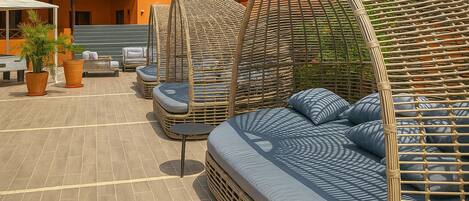Outdoor seating with wicker furniture and cushions, a tiled floor, and potted plants.