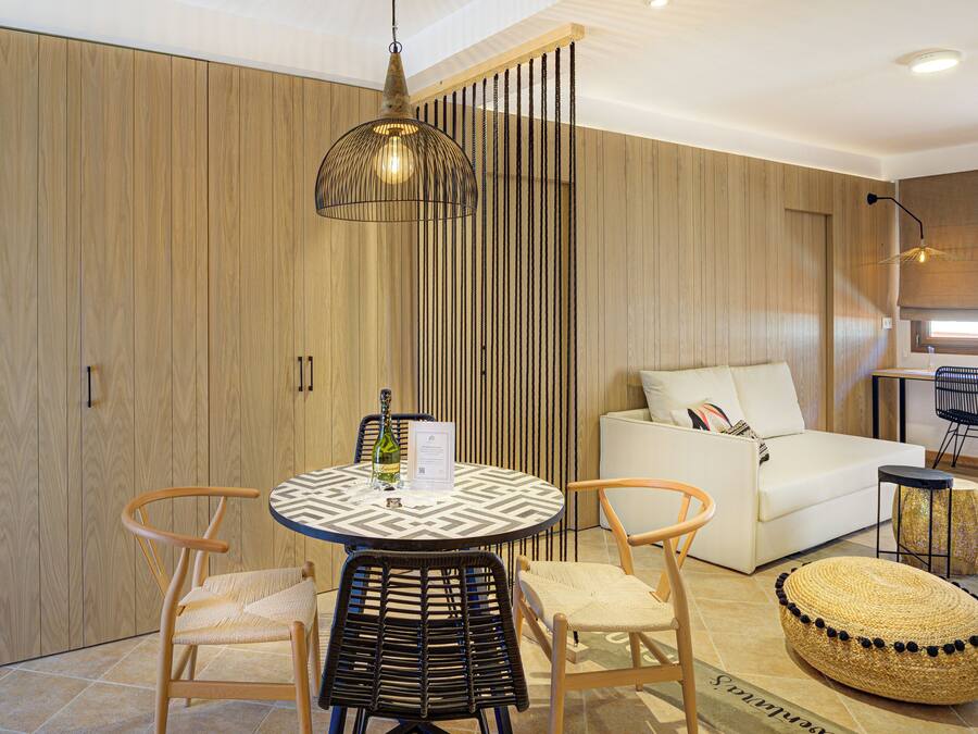 A modern living room with a round table, two chairs, a sofa, and a small ottoman.