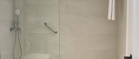 A modern bathroom with a glass-enclosed shower, a toilet, and a towel rack.