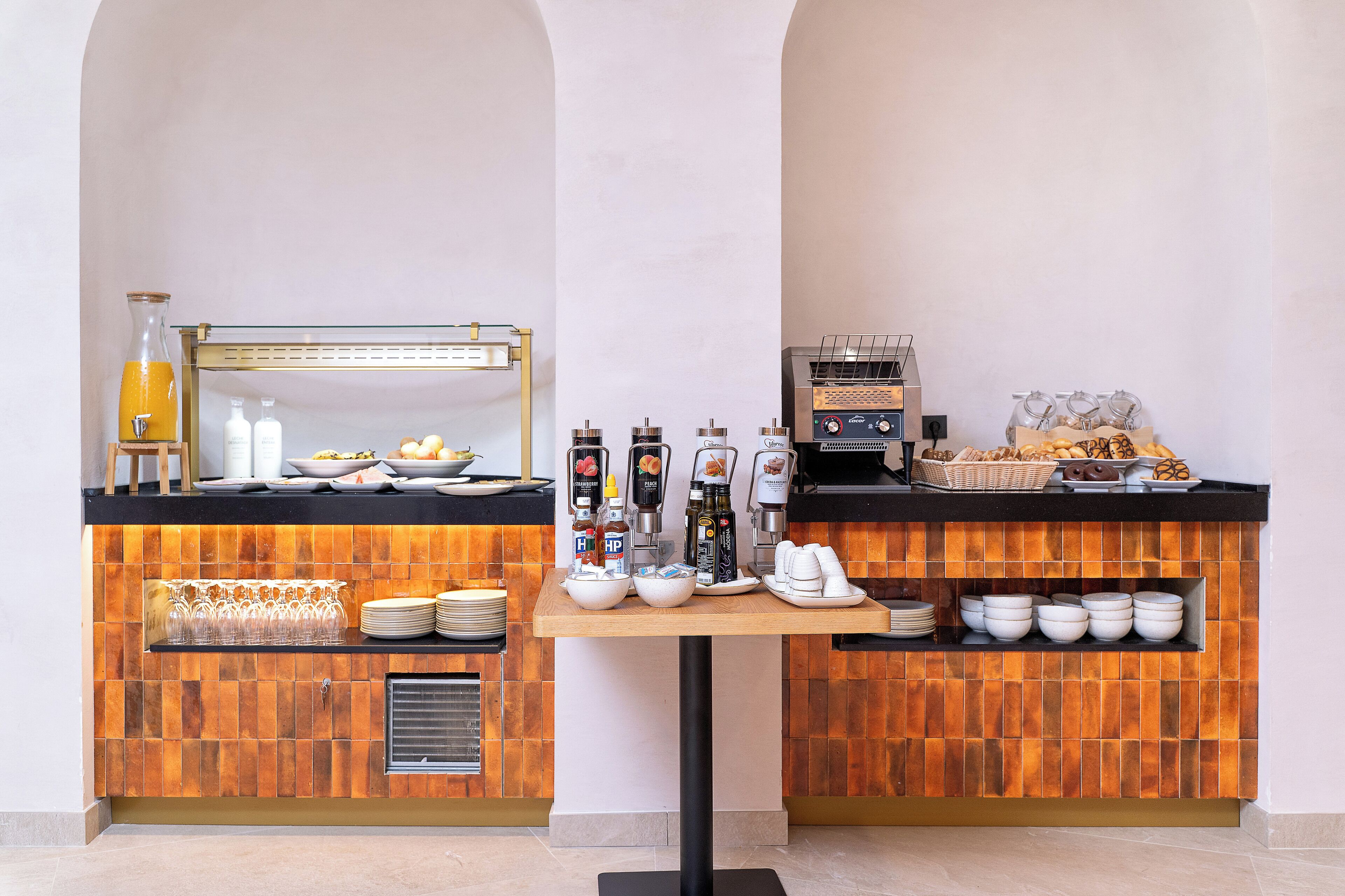 A breakfast bar with coffee machines, a juice dispenser, and a variety of breakfast items.
