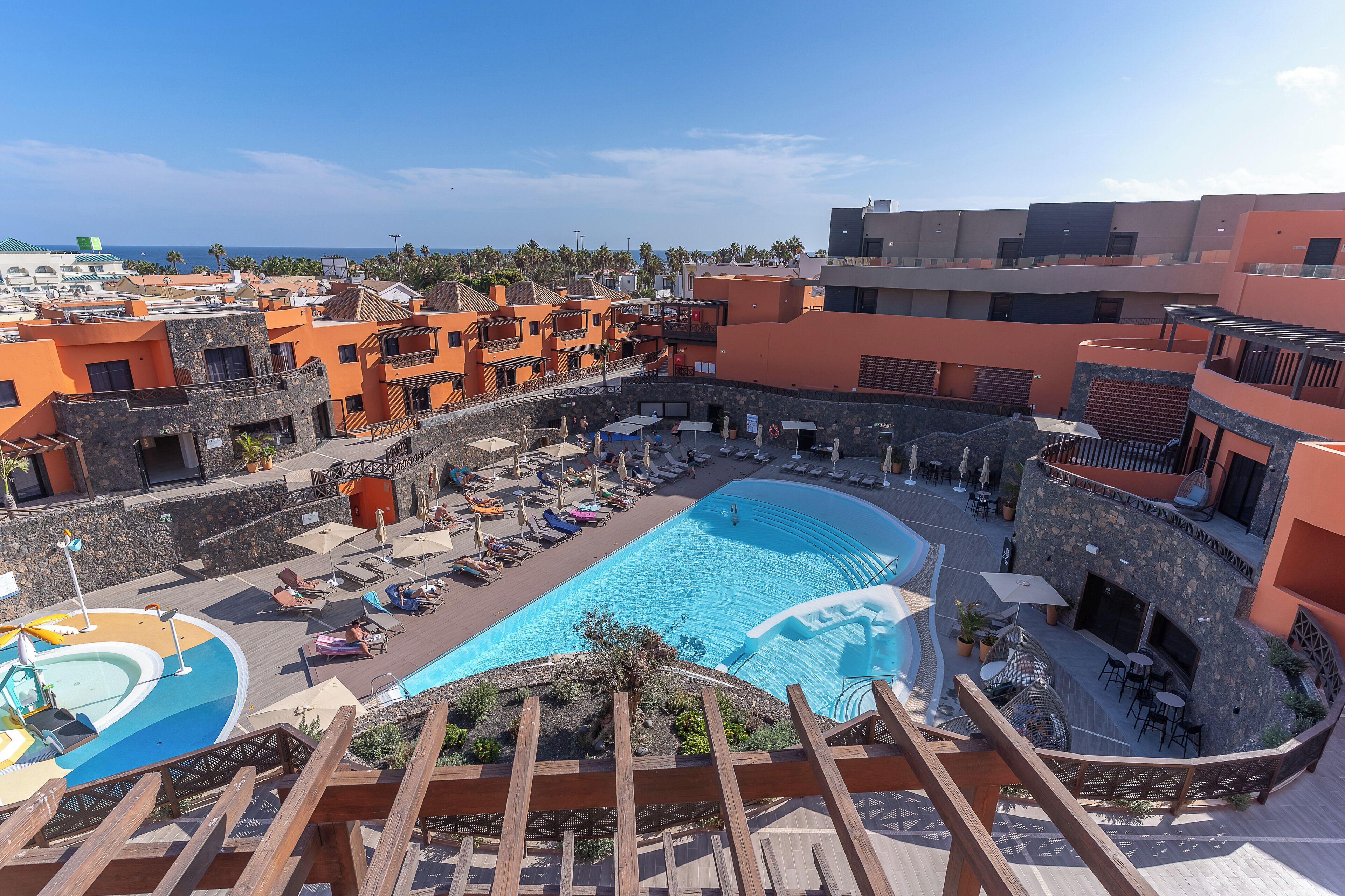 A resort with a large pool, outdoor seating, and a view of the ocean.