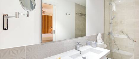 A modern bathroom with a large mirror, a sink, a toilet, and a shower.