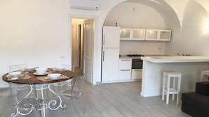 Une cuisine moderne avec des meubles blancs, un îlot central et un coin repas comprenant une table ronde et des chaises.
