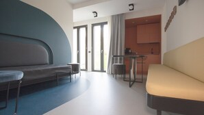 Un espace de vie moderne avec un canapé, une petite table et une cuisine en arrière-plan.