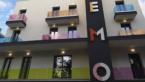 Un bâtiment moderne doté de balcons et d’une enseigne verticale avec des lettres.