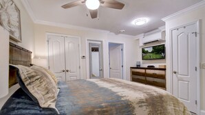 A bedroom with a bed, a ceiling fan, a television, and a dresser.