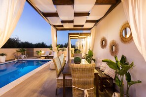 A poolside area with a wooden deck, wicker furniture, and potted plants. - Villa Elisabeth View luxurious with POOL & BBQ !!! (CHANIA GREECE)