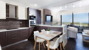 A modern kitchen with dark cabinetry, a dining area with a glass table, and a view of the outdoors. - Villa Elisabeth View luxurious with POOL & BBQ !!! (CHANIA GREECE)