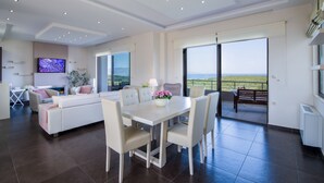 A modern living room with a dining area, large windows, and a flat-screen TV. - Villa Elisabeth View luxurious with POOL & BBQ !!! (CHANIA GREECE)