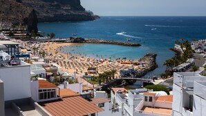 Una località balneare con spiaggia, scogliere rocciose e un molo.