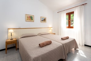 Two beds, a bedside table with a lamp, and framed pictures adorn this inviting room.