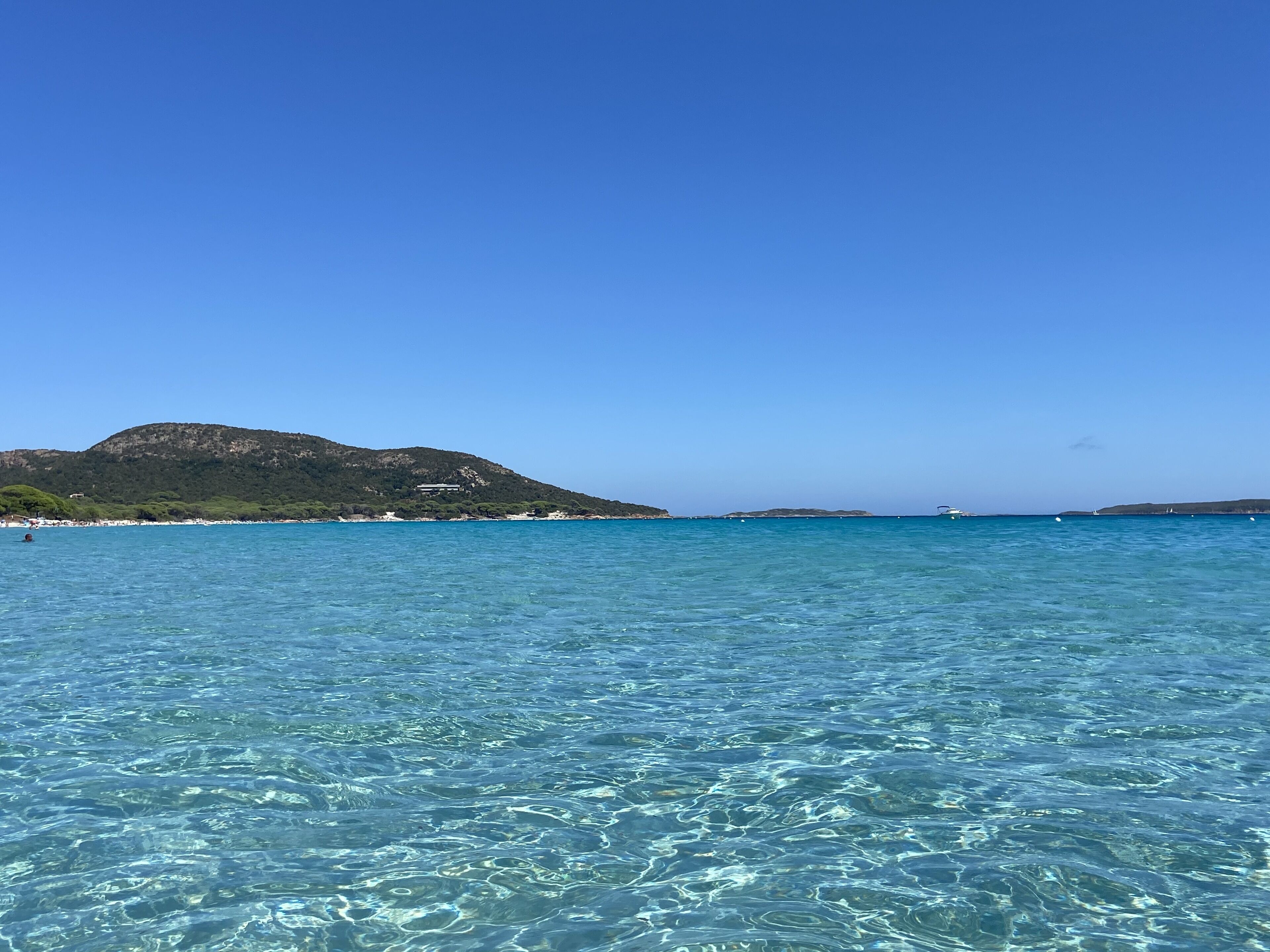 A clear view of a coastal area with a mountain in the background and calm sea water.
