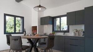 Een moderne keuken met donkere kastjes, een ronde eettafel met vier stoelen en een hangende lamp.