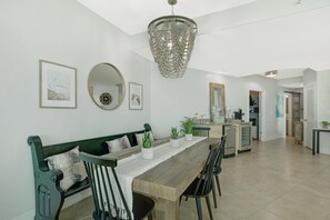 A dining area with a wooden table, green upholstered bench, and a chandelier.