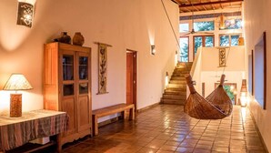 Un intérieur chaleureux avec un meuble en bois, un fauteuil suspendu et un escalier menant à un niveau supérieur.