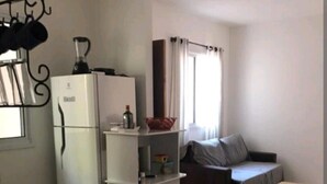 Cocina compacta con refrigerador, microondas y pileta. Peque ño comedor con mesa y banco.
