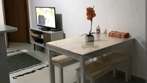 Una sala de estar pequeña y moderna con televisor, una mesa de comedor y un banco.