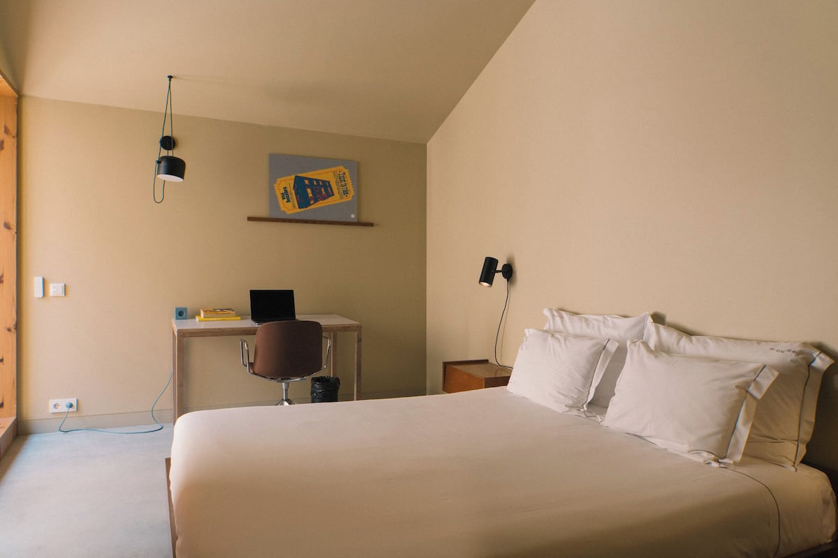Ein Hotelzimmer mit Bett, Schreibtisch, Stuhl und einer Wandlampe.