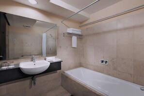 Een moderne badkamer met een wit wastafel, spiegel en bad.