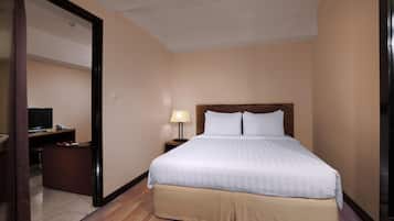 A hotel room with a large bed, a desk with a lamp, and a television.