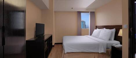 Una habitación de hotel con cama, televisión en una cómoda, ventana con vistas y una puerta.