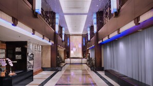 A spacious hotel corridor with a marble floor, a reception desk, and a seating area. - Grand Dafam Braga Bandung (Bandung)
