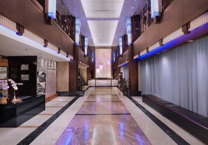 A spacious hotel corridor with a marble floor, a reception desk, and a seating area. - Grand Dafam Braga Bandung (Bandung)