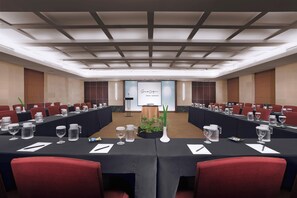 A conference room with a long table, red chairs, and a presentation screen. - Grand Dafam Braga Bandung (Bandung)