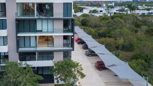En moderne bygning med flere etager, parkeringsplads og udsigt over det omkringliggende landskab.