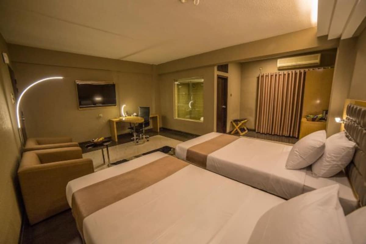 Une chambre d’hôtel avec deux lits, un bureau, une chaise, une télévision et un appareil de climatisation.