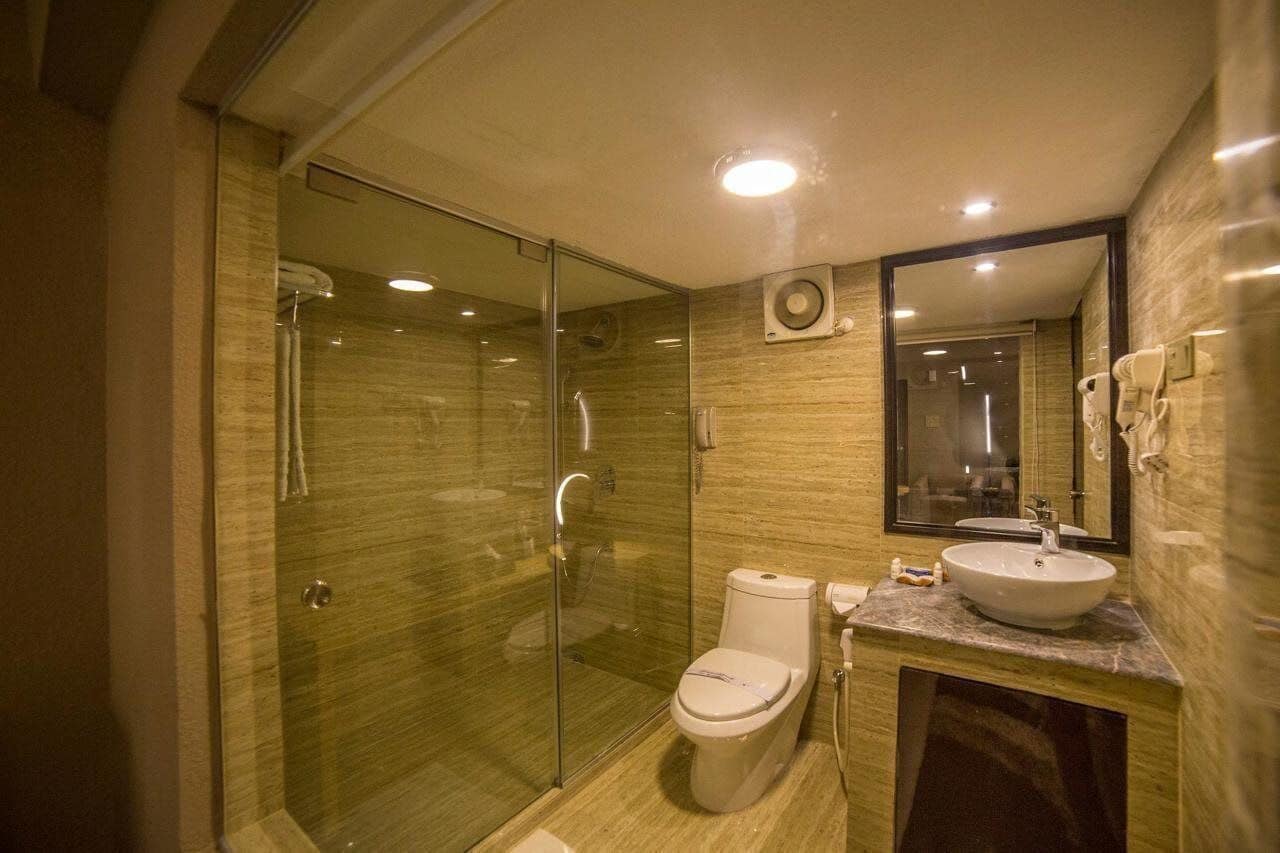A modern bathroom with a glass-enclosed shower, a toilet, and a sink with a mirror above it.