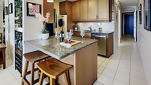 Een moderne keuken met een centraal eiland, houten barkrukken, een wijnfles en glazen.