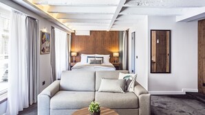 Una habitación de hotel moderna con una cama grande, un sofá, una pequeña mesa de centro y una pared de acento de madera.