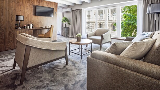 Una sala de estar moderna con un sofá, sillones, una mesa de centro y un televisor instalado en una pared de madera.