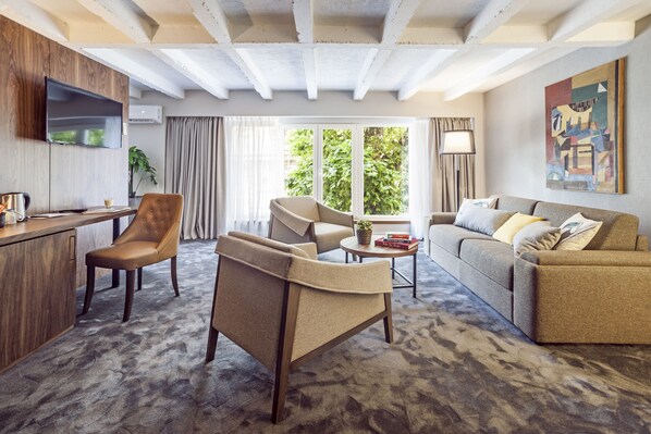 A modern living room with a sofa, armchairs, a coffee table, and a TV mounted on a wooden wall. - Nomad Luxury Suites (Belgrade)