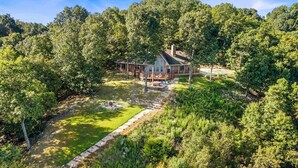 Ein Haus, umgeben von dichtem Wald, mit einem gepflegten Rasen und einer Terrassenfläche.