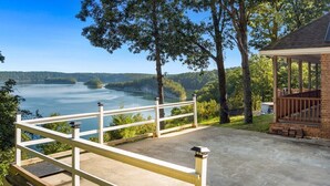 Ein Pavillon mit Betonplatten, mit Blick auf einen See, Bäume und ferne Hügel.