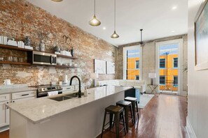 Modern kitchen with a large island, sink, and ample counter space, featuring shelves and modern appliances.