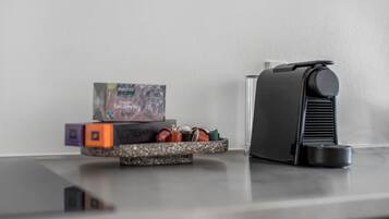A modern kitchen with a coffee machine, a small shelf with a box and some colorful items, and a countertop.