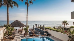 A poolside area with lounge chairs and umbrellas, overlooking the sea. - Soleil Rooms & Suites (Hersonissos)