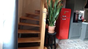 Una escalera con escalones de madera, un refrigerador rojo y una planta en maceta.